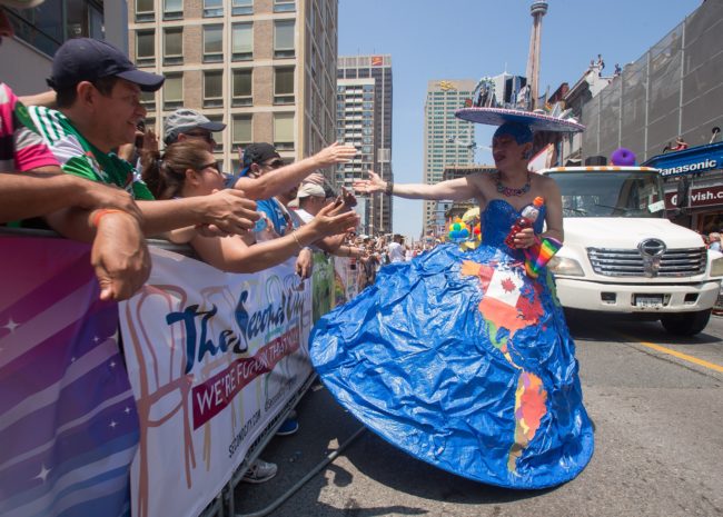 A drag queen with an elaborate model of Toronto as a hat gets high 5's as the WorldPride Parade makes its way down Yonge Street in Toronto, Ontario, Canada, June 29, 2014.  WorldPride is an event that promotes lesbian, gay, bisexual and transgender (LGBT pride) issues on an international level through parades, festivals and other cultural activities.  2014 host Toronto is the first WorldPride celebration ever held in North America, and the 4th such festival in the world.  AFP PHOTO / Geoff ROBINS        (Photo credit should read GEOFF ROBINS/AFP/Getty Images)