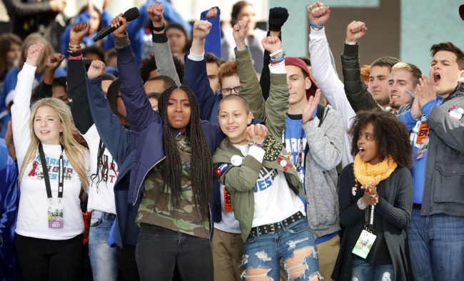 WASHINGTON, DC - MARCH 24:  Students from Marjory Stoneman Douglas High School, including Emma Gonzalez (C), stand together on stage with other young victims of gun violence at the conclusion of the March for Our Lives rally on March 24, 2018 in Washington, DC. Hundreds of thousands of demonstrators, including students, teachers and parents gathered in Washington for the anti-gun violence rally organized by survivors of the Marjory Stoneman Douglas High School shooting on February 14 that left 17 dead. More than 800 related events are taking place around the world to call for legislative action to address school safety and gun violence.  (Photo by Chip Somodevilla/Getty Images)