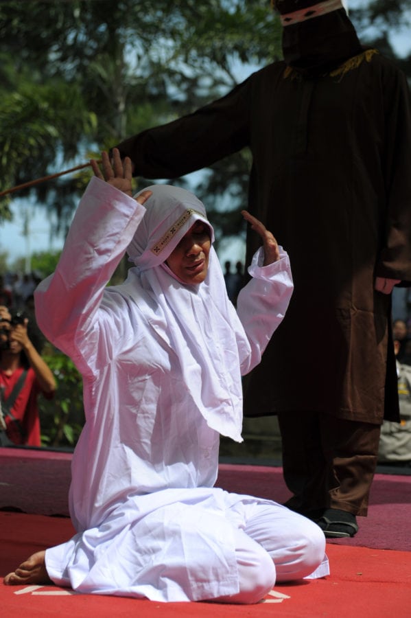 A religious officer canes an Acehnese woman (L) for spending time in close proximity with a man who is not her husband, which is against Sharia law, in Banda Aceh on November 28, 2016. Aceh is the only province in the world's most populous Muslim-majority country that imposes sharia law. People can face floggings for a range of offences -- from gambling, to drinking alcohol, to gay sex. / AFP / CHAIDEER MAHYUDDIN (Photo credit should read CHAIDEER MAHYUDDIN/AFP/Getty Images)