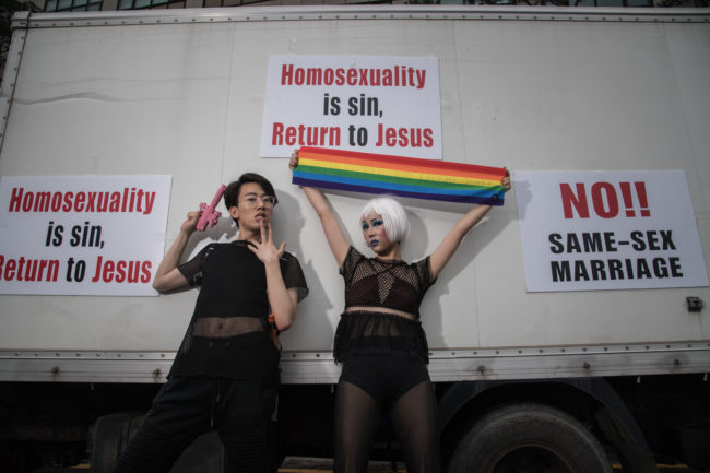 Participants pose for a photo before anti-gay slogans left by homophobes.
