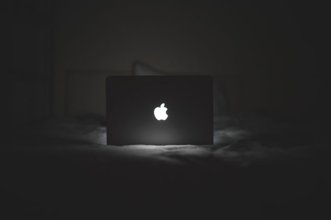 A laptop on a bed in the dark