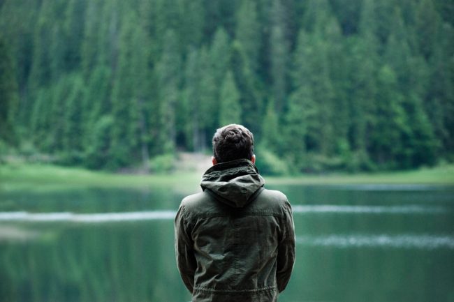 A man stares out at a lake