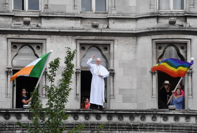 La bandera irlandesa y una bandera del arco iris se colocan a cada lado de un modelo del Papa Francisco durante su visita a Irlanda.