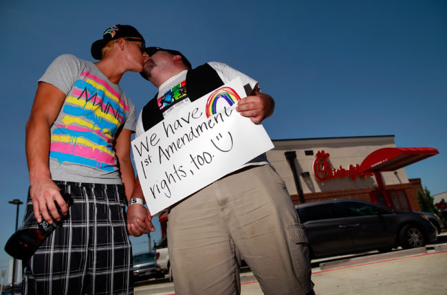 Same sex couple kiss outside a Chick-fil-A, which Rider University banned from its campus causing a dean to resign.