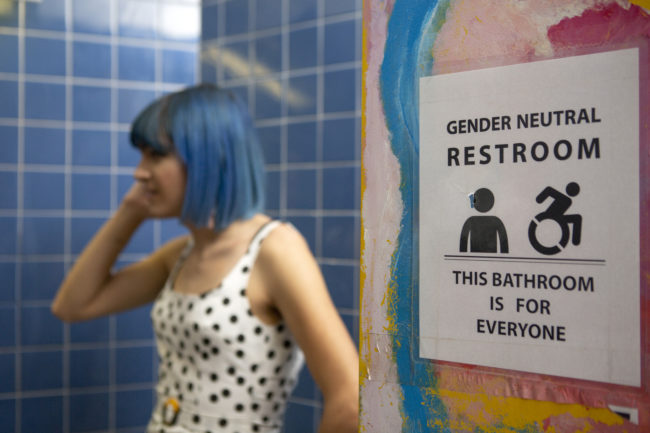 A non-binary femme in a gender neutral bathroom. (