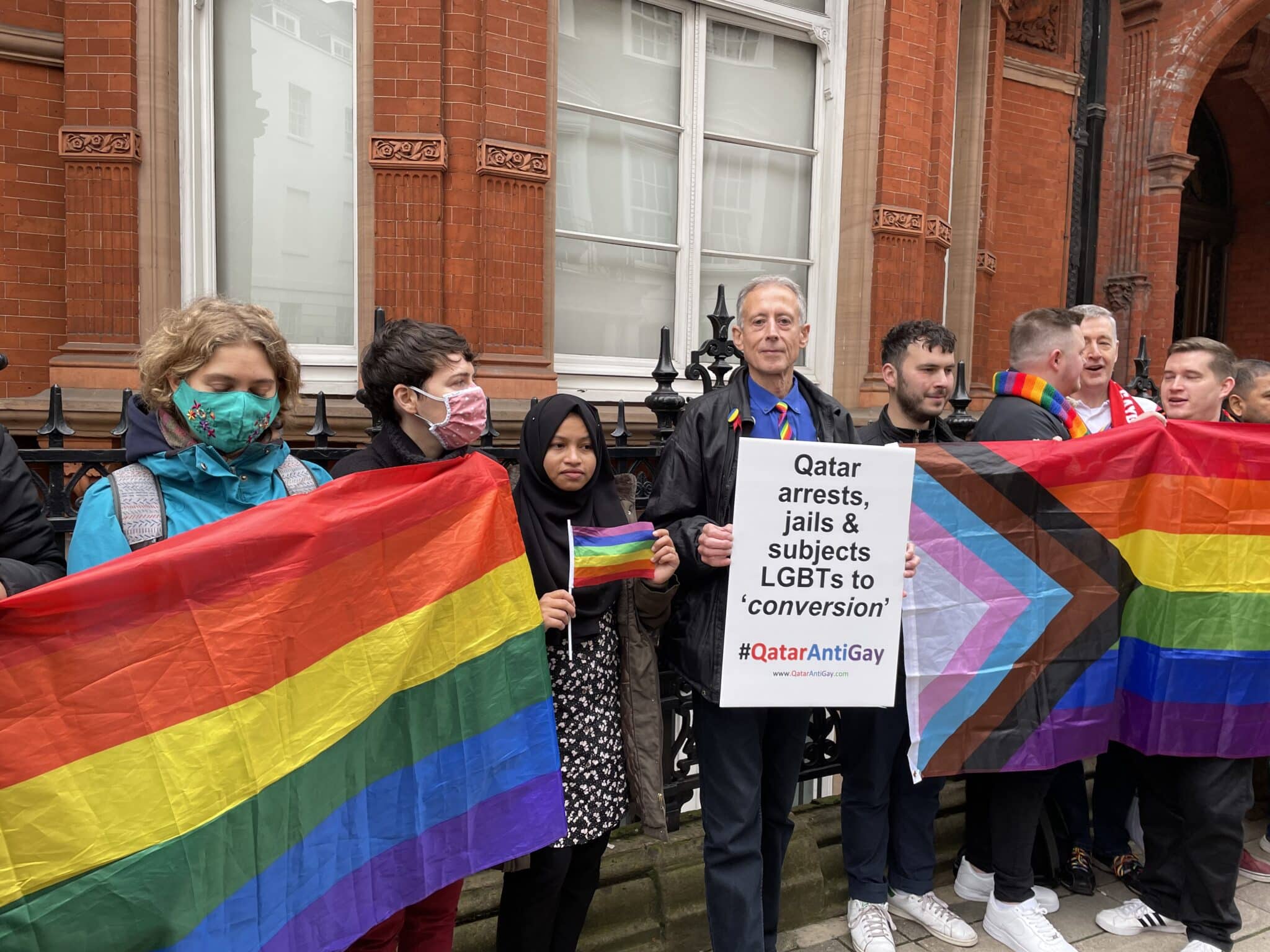 Peter Tatchell holds up a placard that reads 'Qatar arrests, jails & subjects LGBTs to conversion.' 